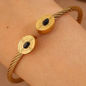 Détail macro du bracelet torsadé doré avec pierres noires ovales et motifs de rayons
