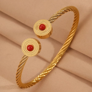 Détail d'un bracelet câble doré torsadé avec pierres rouges et texture ondulée