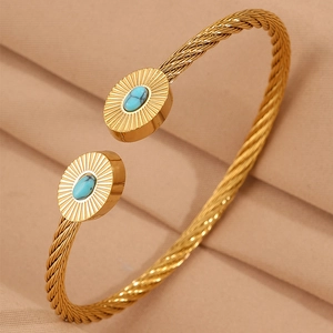 Détail d'un jonc torsadé doré avec pierre turquoise ovale et texture rayons de soleil