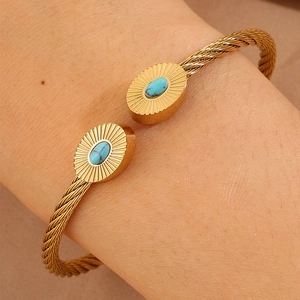 Détail du bracelet câble doré avec extrémités ovales en turquoise et gravure soleil