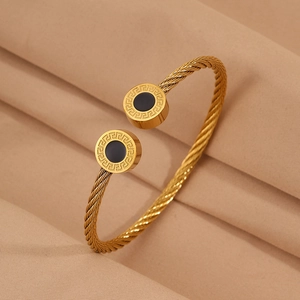 Détail du bracelet câble doré avec motif clé grecque et incrustation noire élégante