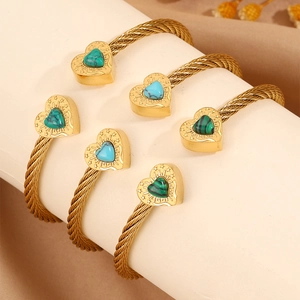 Detailed shot of gold-plated twisted cable bangles featuring heart-shaped gemstones