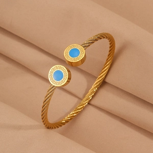 Détail du bracelet câble doré avec pierre bleue et motifs de clé grecque