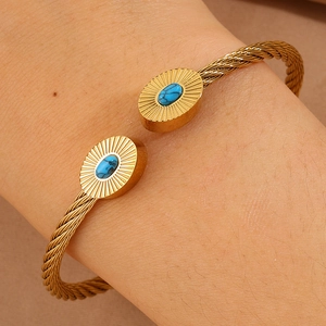 Détail d'un bracelet câble torsadé avec pierre ovale turquoise et acier plaqué or 18 carats