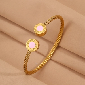 Détail d'un bracelet câble torsadé doré avec motif de méandres grecs et inserts roses