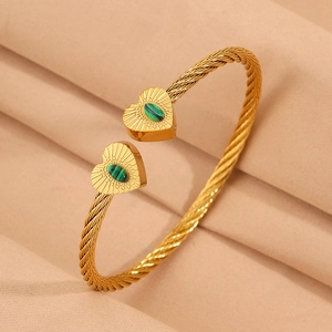 Close-up of twisted gold bracelet featuring heart ends with green malachite inlay
