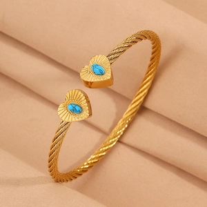 Detail of twisted gold wire bracelet with heart charms and blue turquoise stone inlay