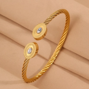 Détail du bracelet jonc doré torsadé orné d'incrustations de pierres de marbre blanc
