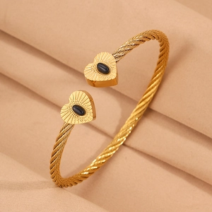 Macro detail of golden cable wire bracelet with heart tips and black gemstones