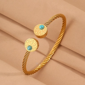 Détail du bracelet en câble doré avec des breloques soleil et étoiles turquoise