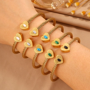Detail of gold-plated twisted cable bangles with multi-colored heart-shaped stone inlays