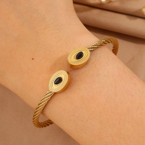 Détail d'un bracelet câble plaqué or 18 carats avec gemmes ovales noires porté au poignet