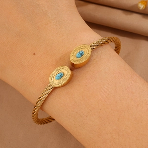 Détail d'un bracelet torsadé en or avec pierres turquoise ovales et plaqué 18K