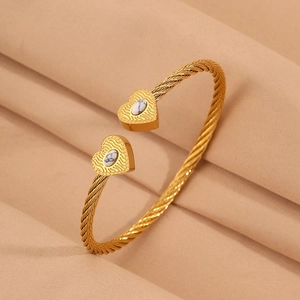 Detail of twisted gold wire bracelet with heart-shaped marble stone ends on satin background