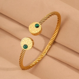 Détail d'un bracelet torsadé doré avec gravure d'étoile et incrustation de malachite verte