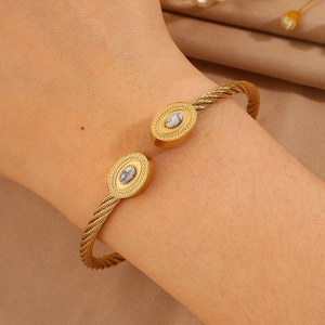 Détail macro du bracelet ouvert doré torsadé avec pierres ovales marbrées et perles