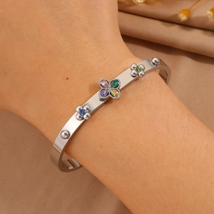 Close-up of silver steel cuff bracelet with colorful clover zircon stones on female wrist