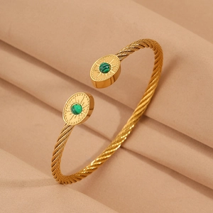 Détail d'un bracelet torsadé ouvert en acier plaqué or 18K avec pierre verte et gravures
