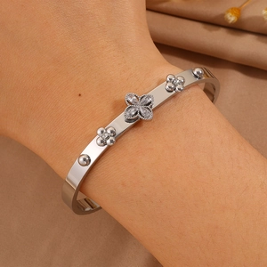 Detail of silver clover bangle with zircon petals on polished stainless steel band