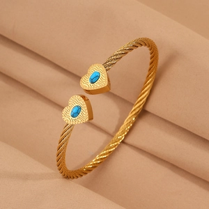 Close-up of twisted cable gold bracelet with blue stone heart-shaped charms