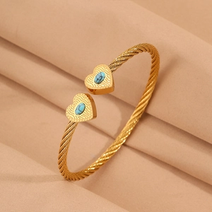 Detailed close-up of gold cable bracelet featuring heart charms and turquoise stones