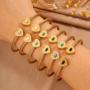 Detail of stacked heart-shaped wire bracelets with multi-colored stone inlays for women