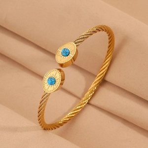 Détail d'un bracelet jonc torsadé doré 18K avec pierres turquoise et motif soleil
