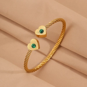 Macro shot of twisted gold cable bracelet with malachite heart charms and sunburst texture