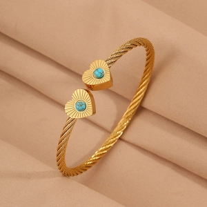 Detail of golden cable cuff bracelet with heart shapes and inlaid turquoise stones