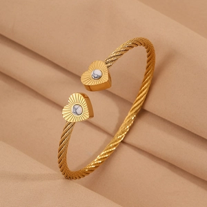 Detail view of gold cable wire bangle featuring heart charms with marble stone inlays