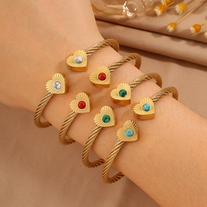 Stackable gold stainless steel cable bangles featuring heart charms with colorful inlay stones