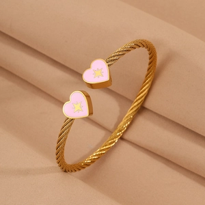 Detailed close-up of gold stainless steel twisted bangle with pink enamel hearts
