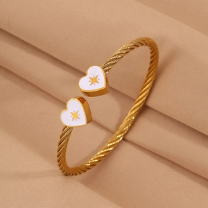 Detail of gold twisted wire bangle featuring white heart charms with starburst patterns