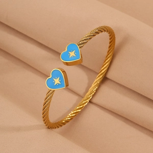 Detailed macro of gold twisted rope cuff with blue enamel heart and gold star charms