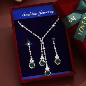 Detalle macro de conjunto joyas de circón verde esmeralda en caja de regalo roja con cinta