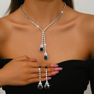 Detalle de collar plateado y pendientes de gota con grandes piedras negras decorativas