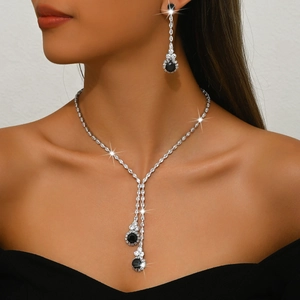 Detalle del conjunto de collar en Y y pendientes plateados con gemas negras óvalo
