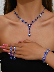 Close-up of sparkling silver necklace and earrings set with deep blue rhinestones on model