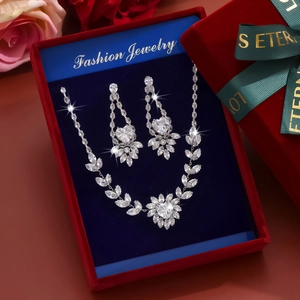 Detailed view of silver zircon necklace and earring set inside a red bow gift box with roses