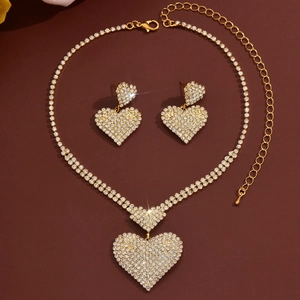 Detalle del conjunto de collar y pendientes de corazón con pedrería en tono dorado