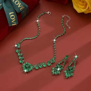 Detail of luxury zircon necklace and earrings set with green heart gems in a gift box