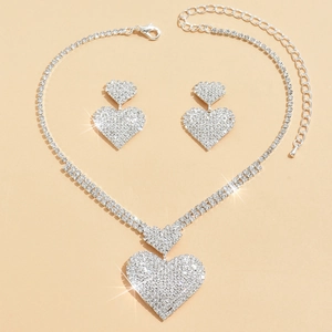 Detalle de un conjunto de joyas con collar y pendientes de corazón en cristal plateado