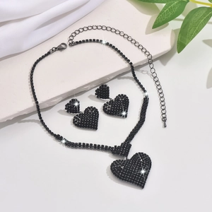 Detalle de un conjunto de collar y pendientes de corazón con diamantes negros en seda