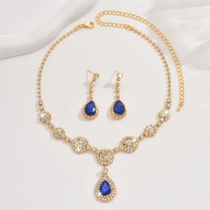Close-up of geometric jewelry set with teardrop blue sapphire zircon stones and gold plating