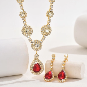 Detail of luxury gold jewelry set with pear-cut red crystals and shimmering rhinestones