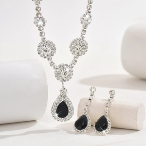 Detail shot of zircon jewelry set with black pear-shaped pendants on white stone block