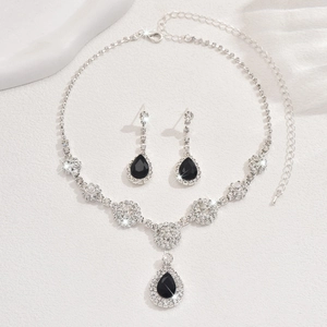Close-up of elegant jewelry set with black teardrop rhinestones on white texture