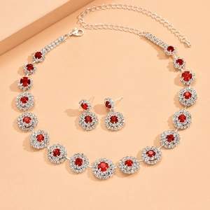 Detalle de conjunto de collar y pendientes de plata con gemas rojas y cristales