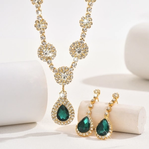 Detailed close-up of emerald pear-cut gemstone necklace and earrings with gold plating