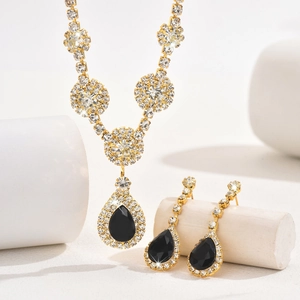Detailed macro view of gold-tone jewelry set with black pear-shaped gemstones and crystals